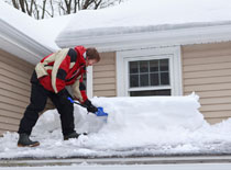 Man shoveling snow off roof
