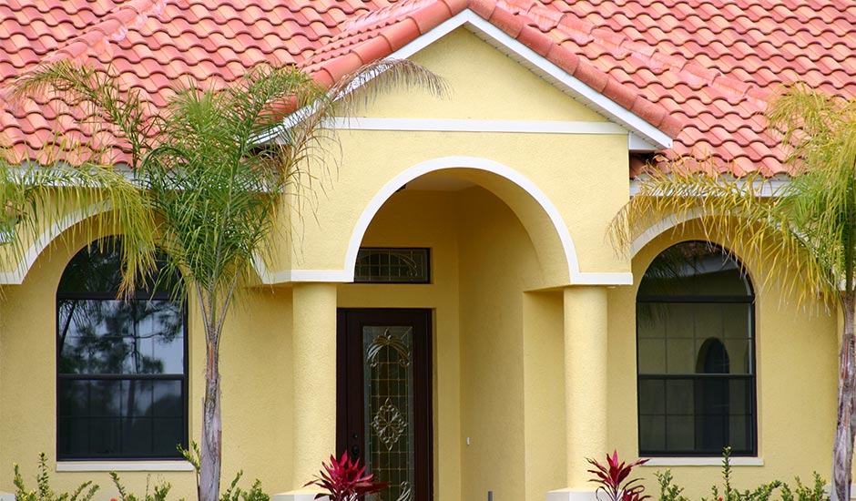 yellow Spanish style home with tile roof
